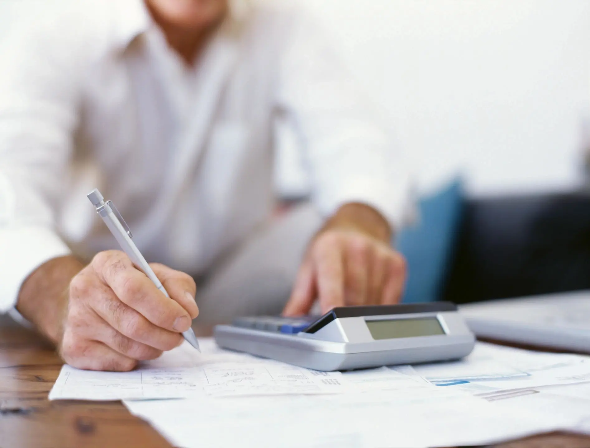 Person calculating finances with pen and calculator.