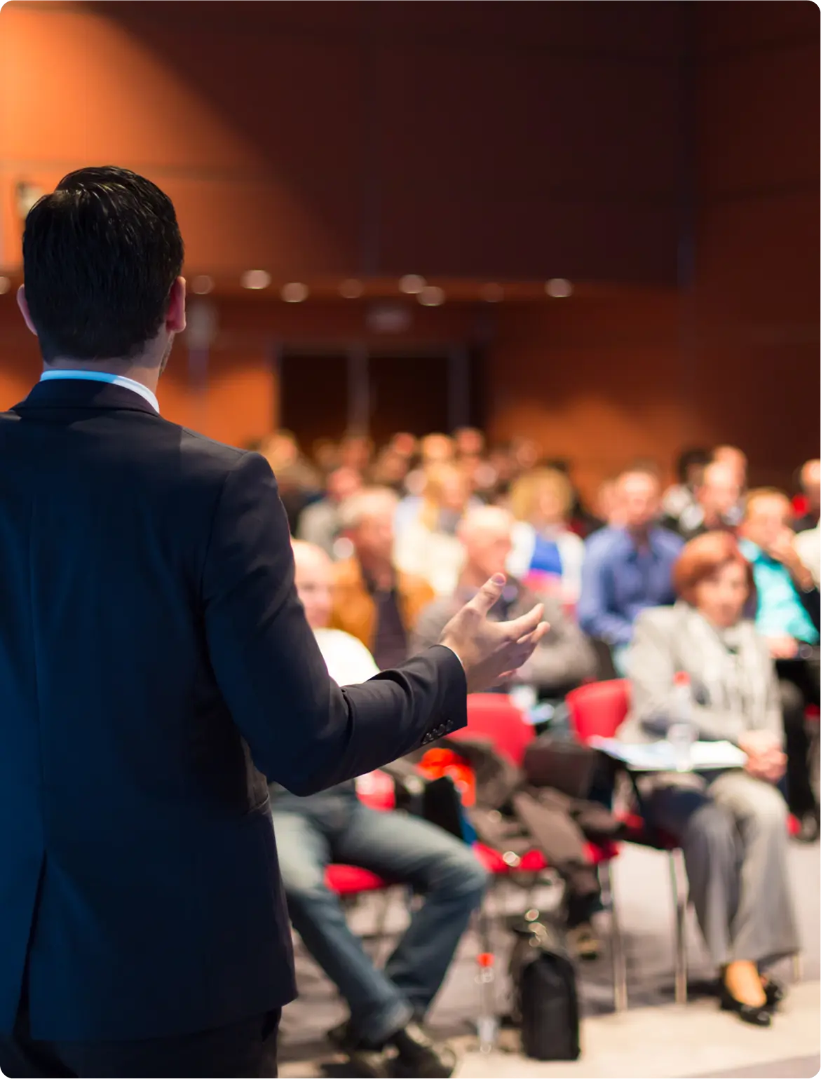 A speaker addressing an engaged audience in a conference room.