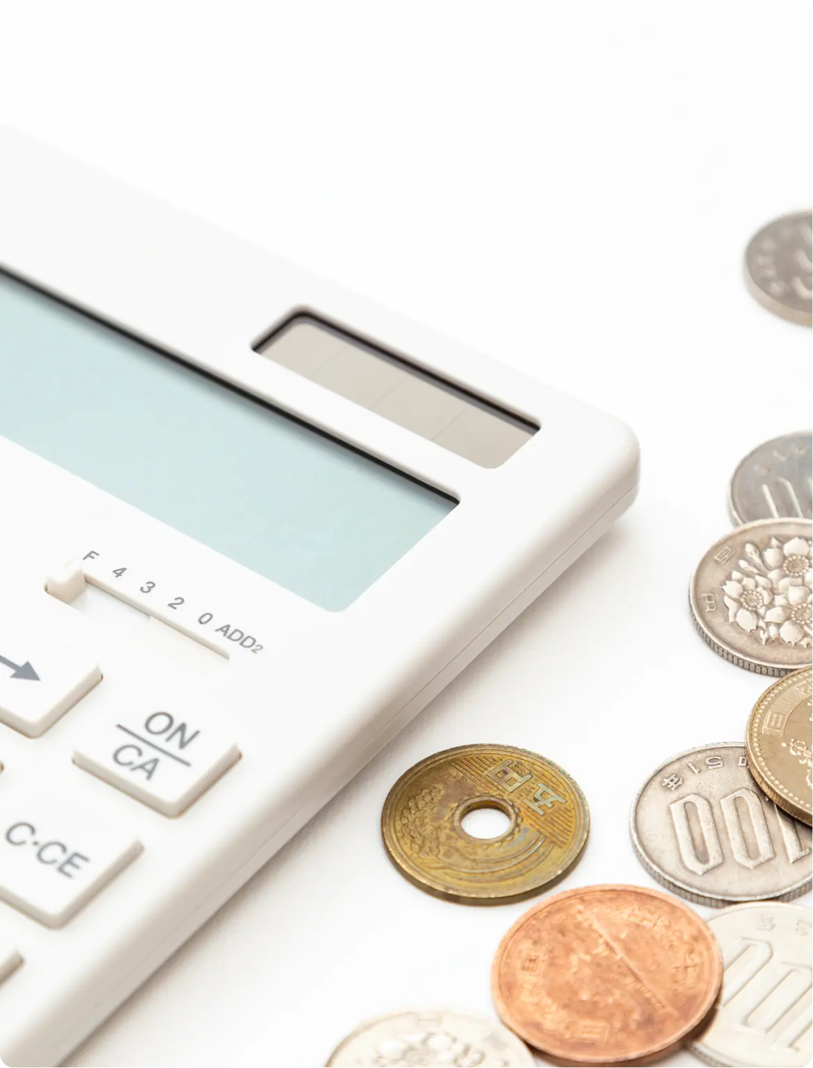 White calculator with various Japanese coins beside it.