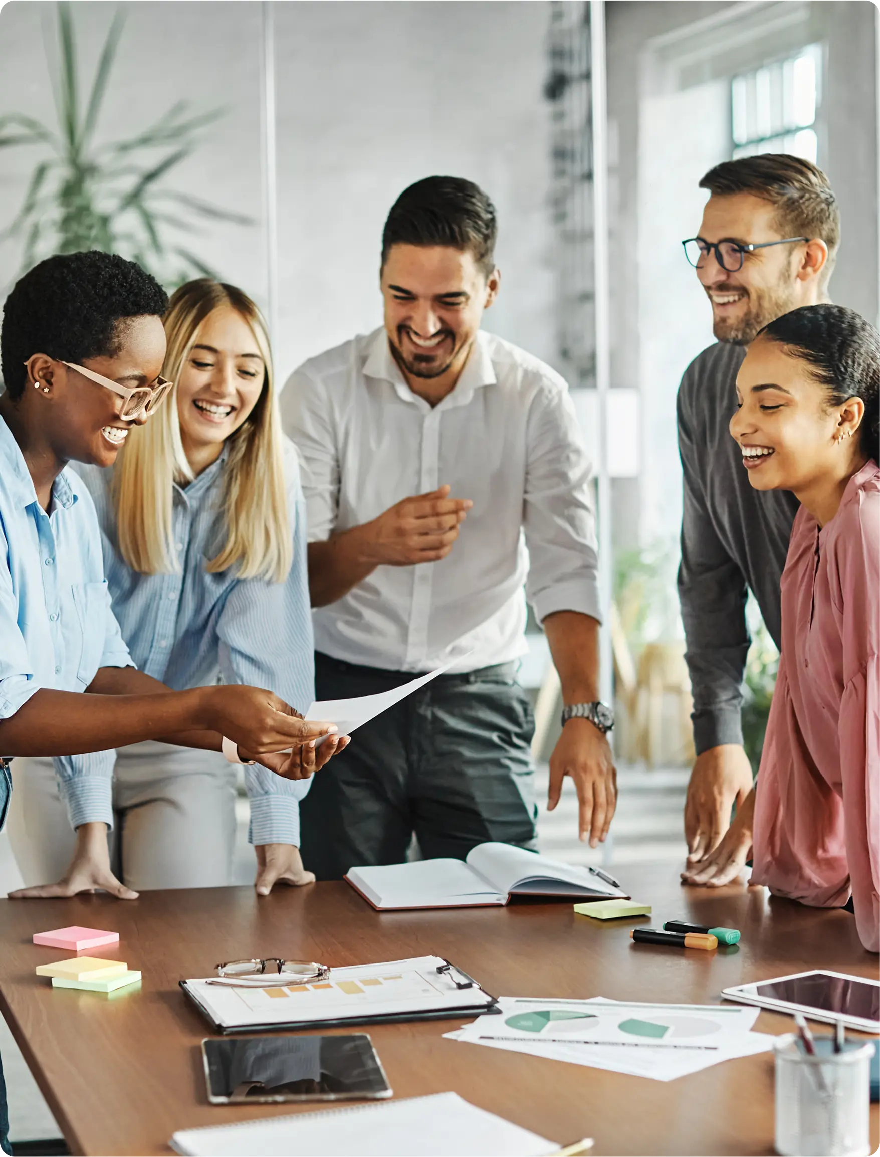 A diverse group collaborating happily around a table in an office.